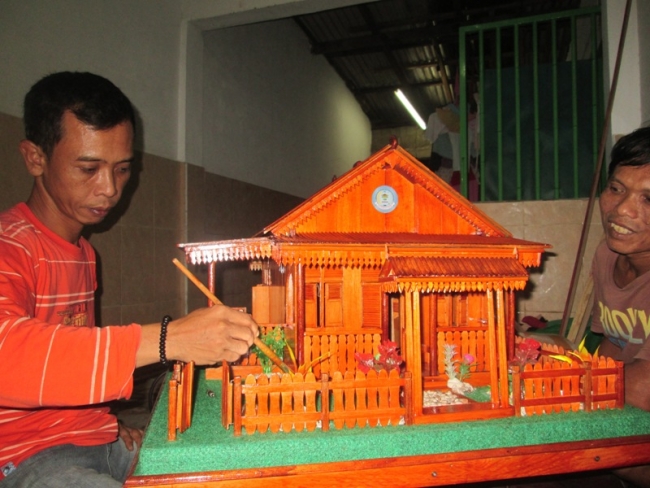 Jamaludin dan rekannya saat mengerjakan miniatur rumah adat Betawi.