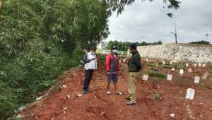 Sejumlah petugas TPU khusus Covid di Jombang Rawalele saat memantau tanah makam yang terancam longsor.