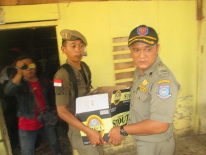 petugas Pol PP Tangsel saat mengamankan satu dus minuman beralkohol dari dalam rumah warga di kawasan Alang-Alang
