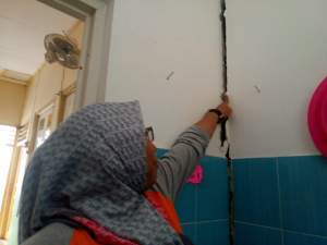 Salah seorang guru SKh Assalam 01 Serpong tunjukan retakan tembok sekolah.