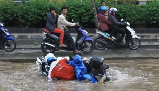 Pengendara motor dan dua penumpangnya terjatuh saat melintas di Jalan Raya Siliwangi, Tangerang Selatan (13/1). Akibat jalan rusak disertai genangan air saat musim hujan menyebabkan banyak pengendara sepeda motor terjatuh.