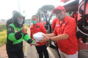 Seorang pengemudi ojek online menerima nasi bungkus dari Ketua DPC PDIP Tangsel, Wanto Sugito.